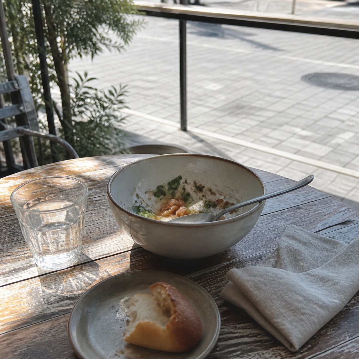 昼の屋外カフェに残る軽い食事と水のグラス